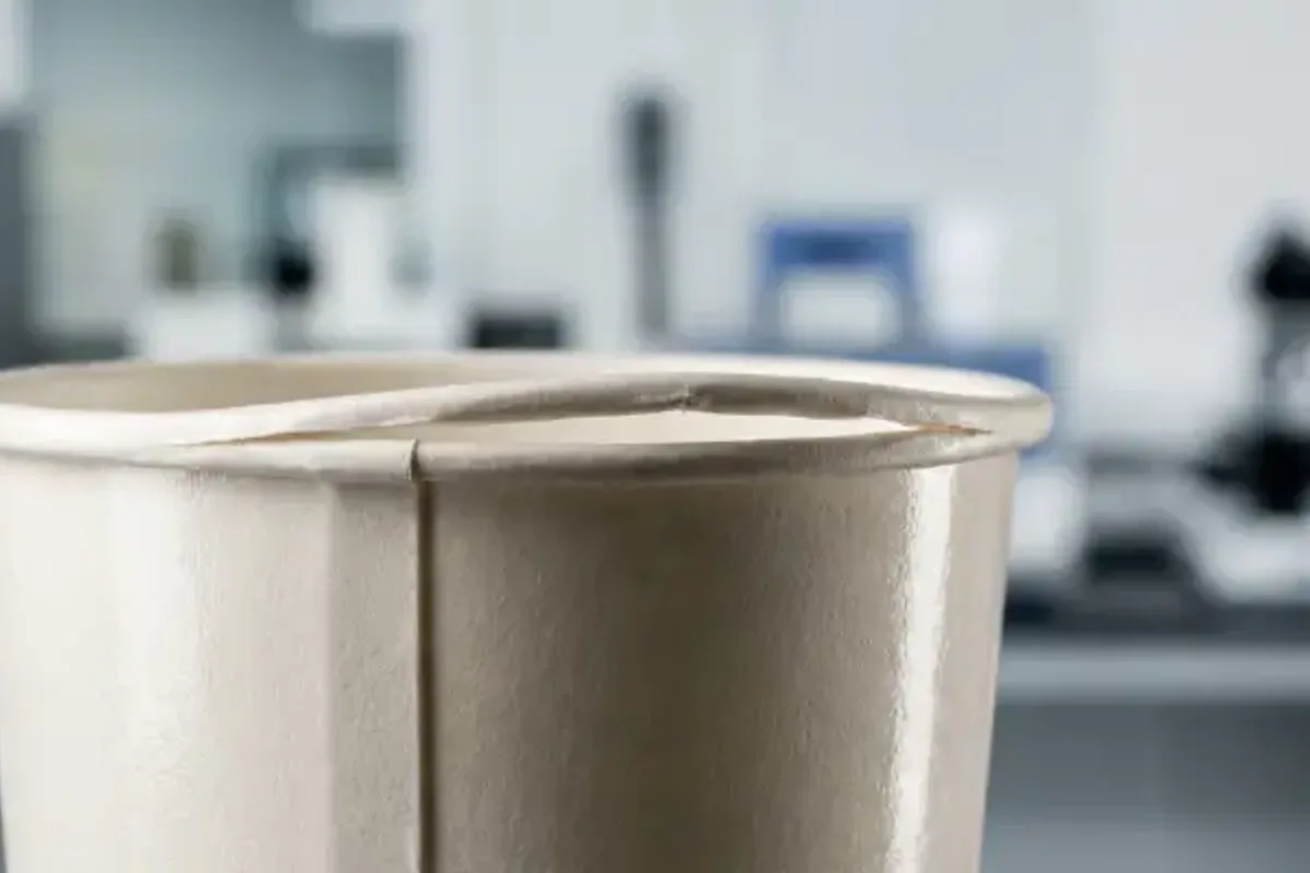 Paper cup side-seam flagging on aqueous-coated stock during production qualification.