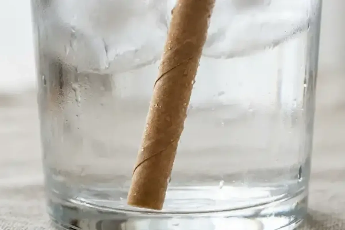 Kraft paper straw standing in water to check adhesive water resistance.