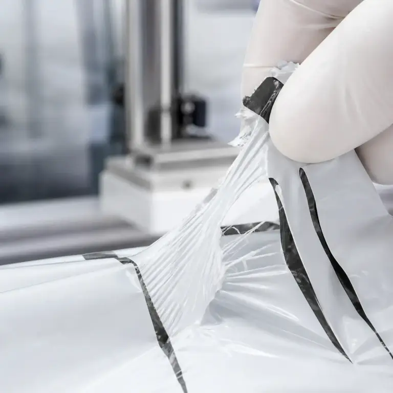 Nozzle applying adhesive to poly mailer film for auto-bagging seal qualification.