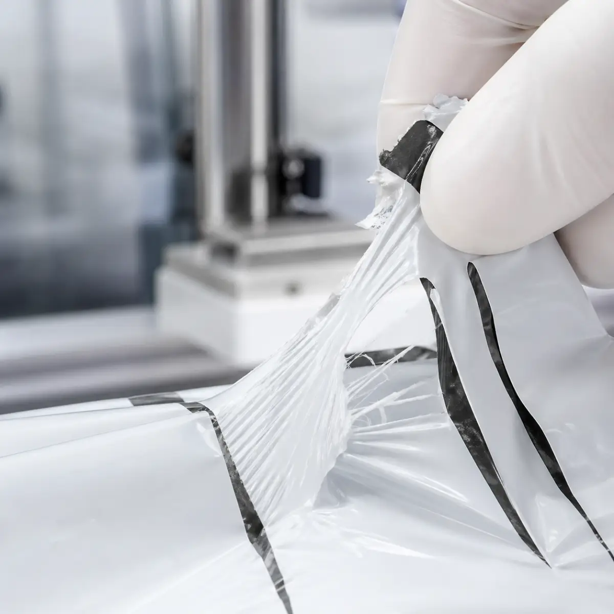 Nozzle applying adhesive to poly mailer film for auto-bagging seal qualification.