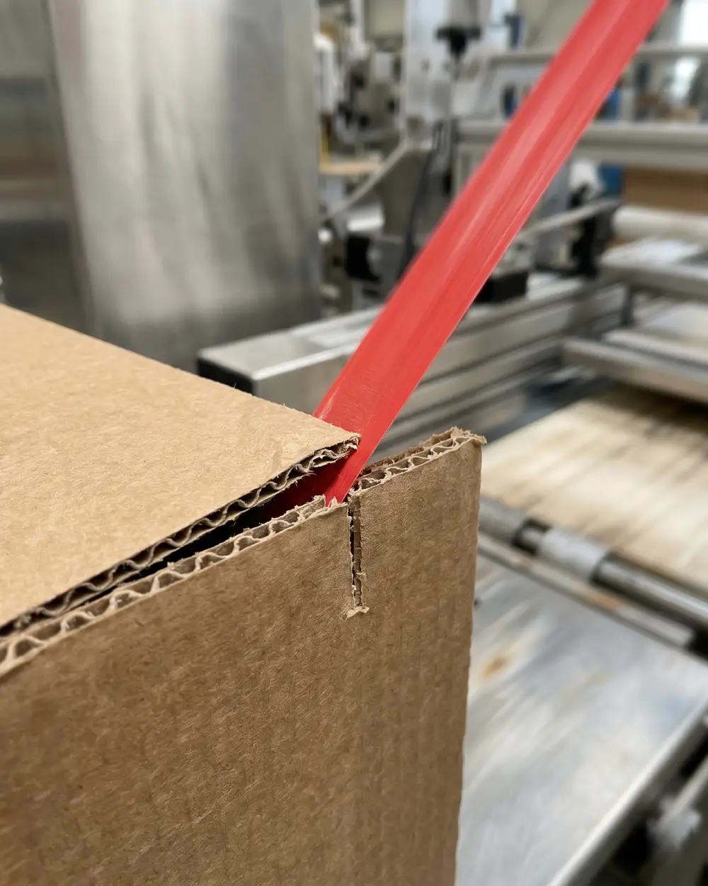 Macro detail of tear tape creating a clean easy-open cut on corrugated packaging